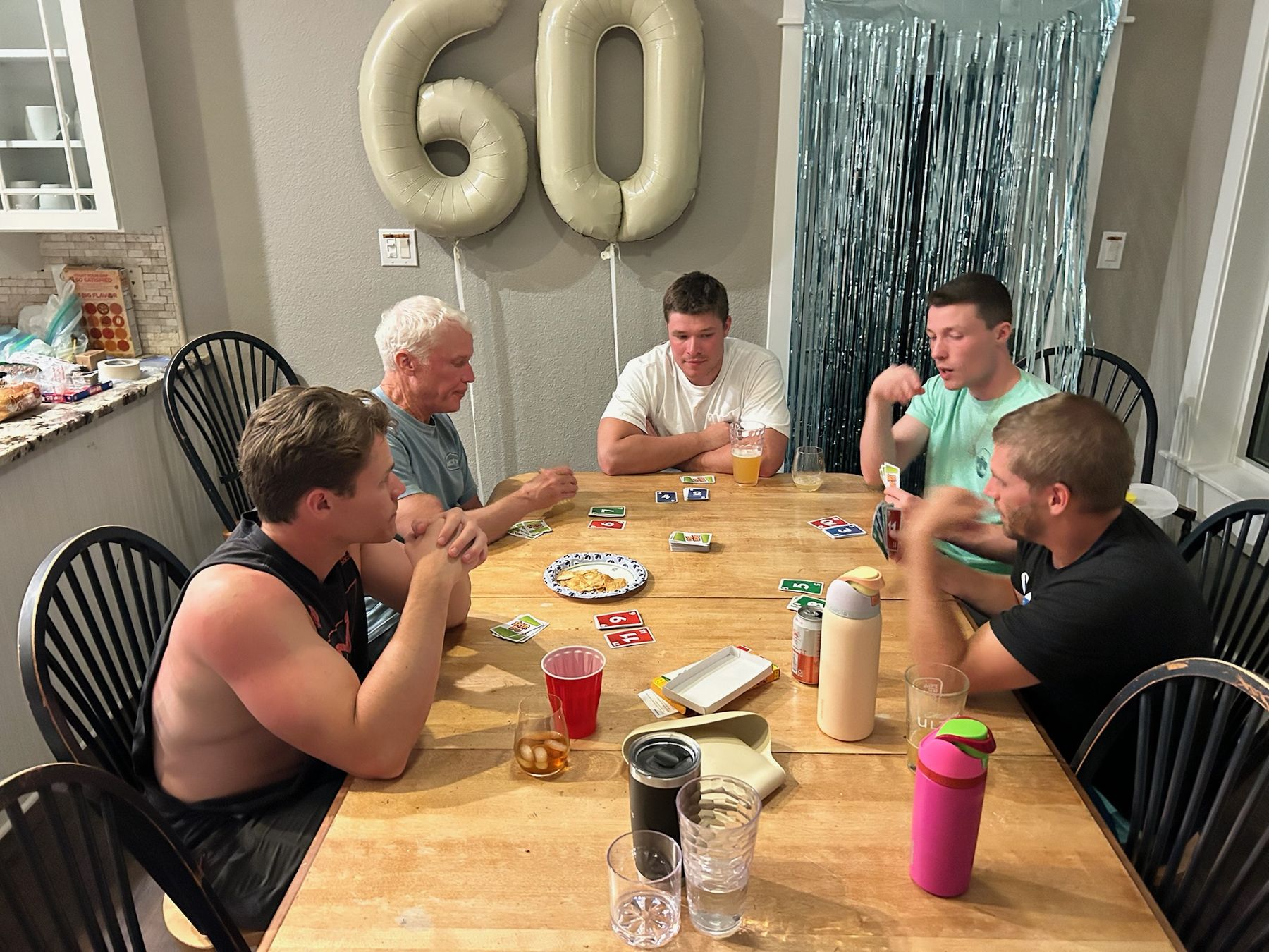 The guys playing Skip-Bo under the 60 balloons